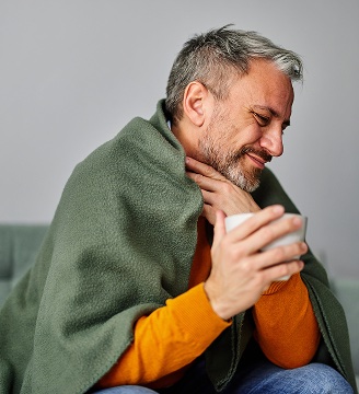 Uomo bruciore gola coperta e tisana